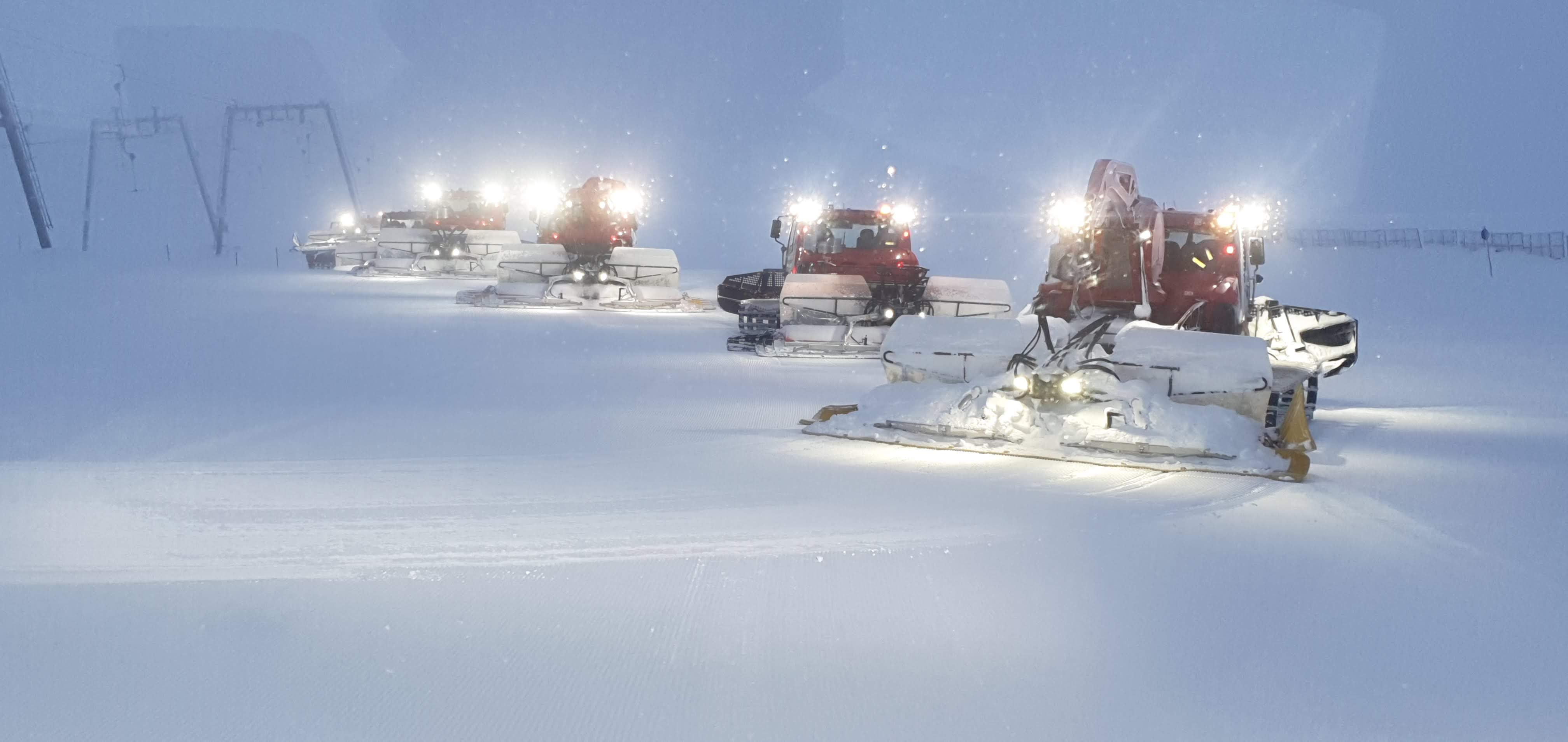 Pistenraupen-Flotte bei Nachtbetrieb